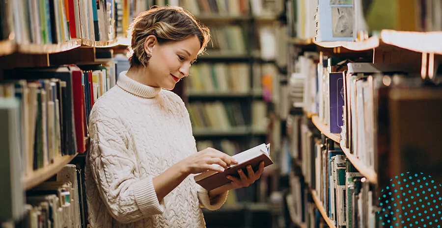 imagem de uma mulher segurando um livro em uma biblioteca